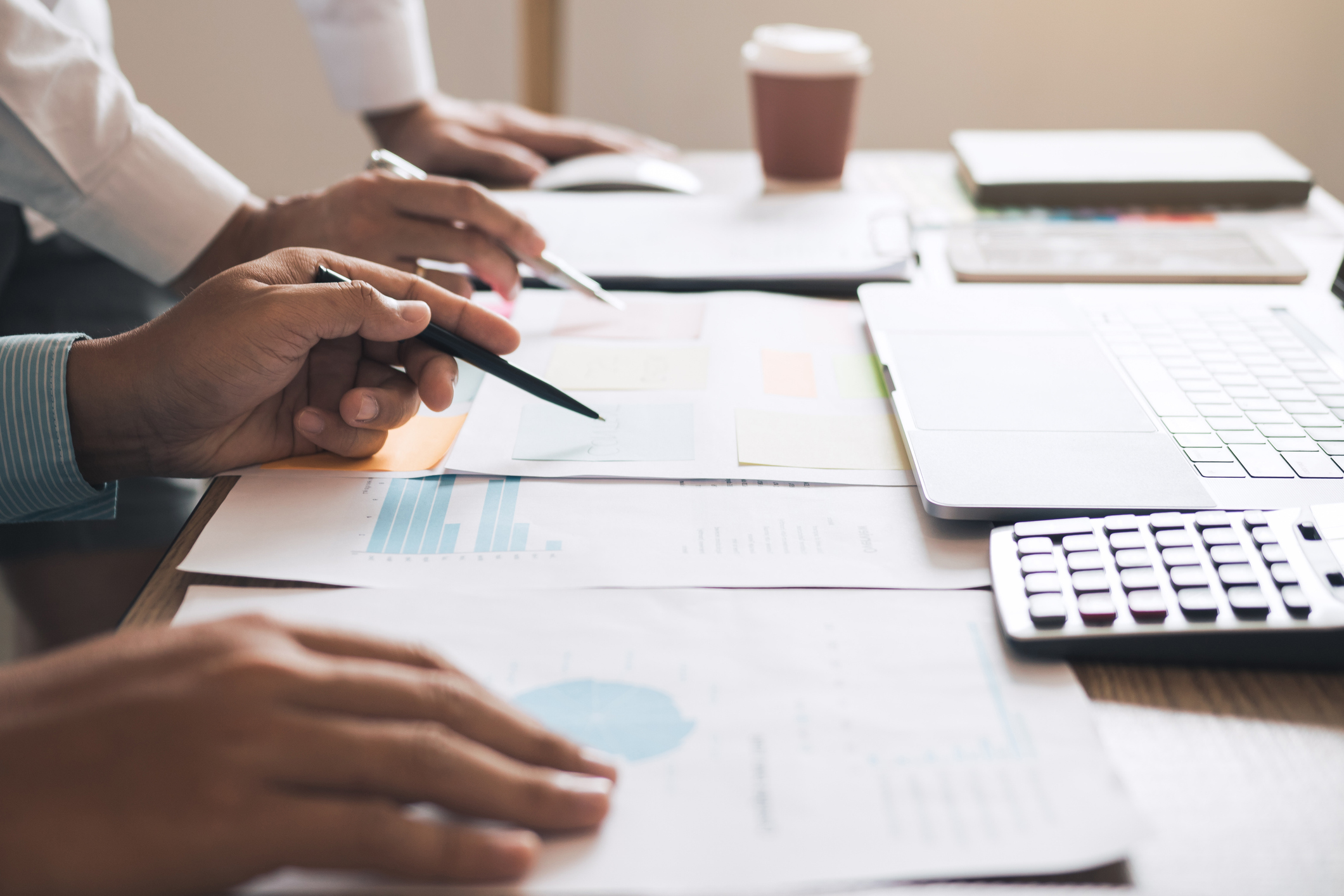 Close-up of business professionals reviewing financial documents and charts at a desk with a laptop and calculator — representing financial planning for home equity loans.