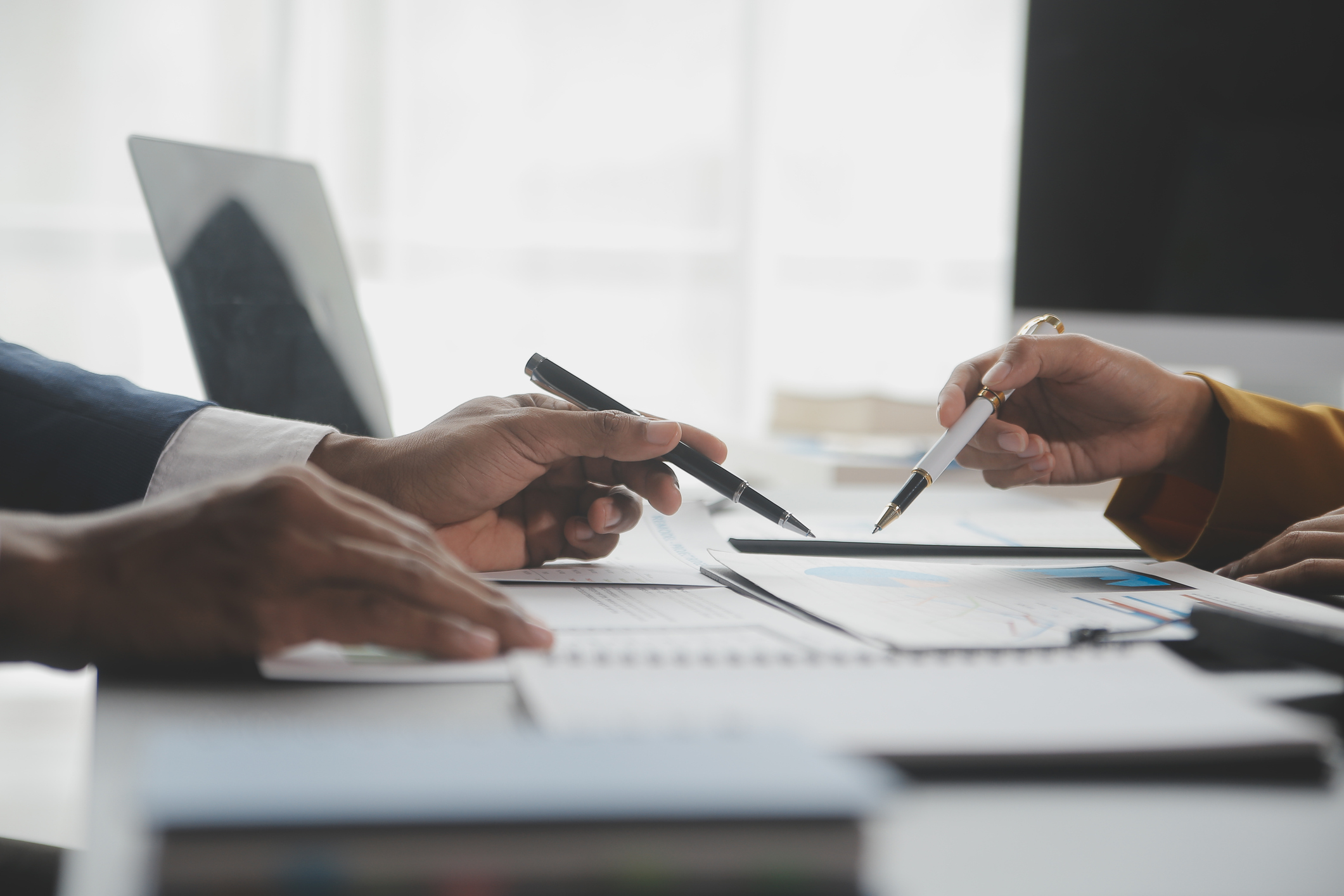 Close-up of professionals in business attire discussing financial charts and documents at a desk — illustrating personalized financial guidance and community-focused banking services.